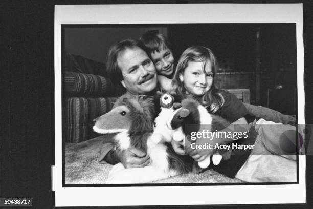 Former child actor Jon Provost from TV series Lassie, w. Daughter Katie & son Ryan clutching Lassie stuffed toy animals while lying on floor in...