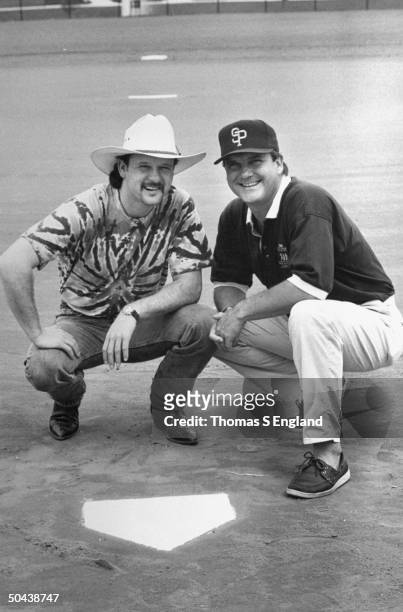 Musician Tim McGraw w. Father, former baseball player Tug McGraw in baseball cap, as they crouch next to home plate on baseball field.