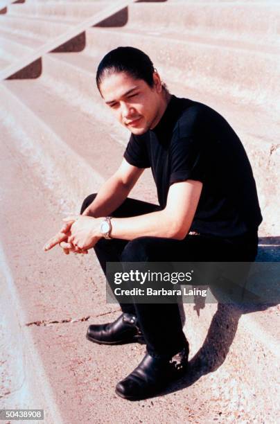 Chris Perez, husband of slain tejano singer Selena, posing outside on concrete steps.