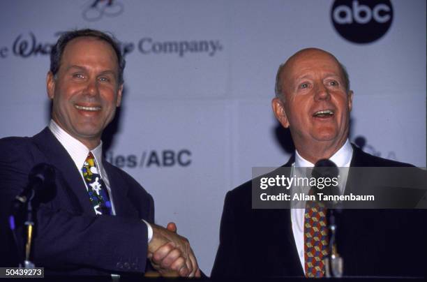 Disney's Michael Eisner & Capitol Cities' Thomas Murphy shaking hands on Disney deal to buy Cap Cities/ABC in merger announced on Good Morning...