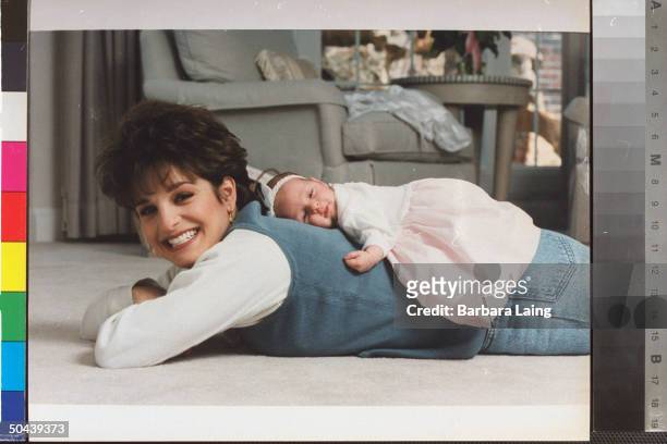 Former Olympic gymnast Mary Lou Retton lying on floor w. Infant daughter Shayla lying on Retton's back in bedrm. At home.