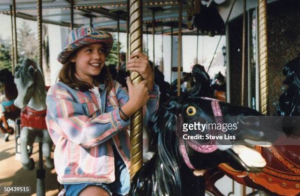 Actress Liesel Matthews star of movie A Little Princess, riding wooden horse on merry-go-round at 6 Flags Great America.