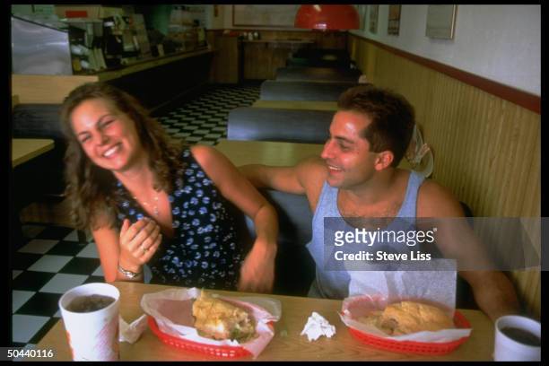 Champion diver Mark Lenzi, who is member of 1996 US Olympic diving team, sharing laugh w. Girlfriend Ramona Benkert at table in restaurant.