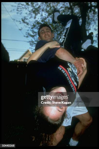 Wrestler Chris Saba holding 19-yr-old actress girlfriend Hillary Wolf, who is member of 1996 Olympic women's Judo team, upside down.