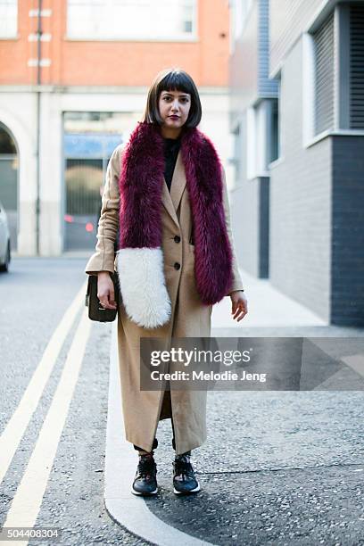 Cathy Bhairo wears a camel Topshop coat, a maroon and white fur shawl, and Nike Air Huarache floral sneakers during The London Collections Men AW16...