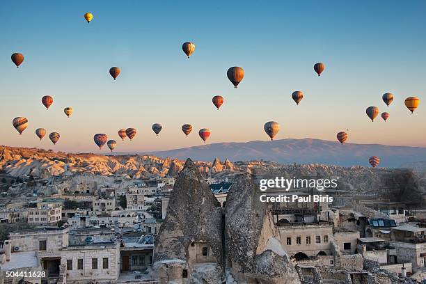 hot air balloons floating over rock formations at sunrise goreme village , cappadocia, anatolia, turkey - göreme stock-fotos und bilder