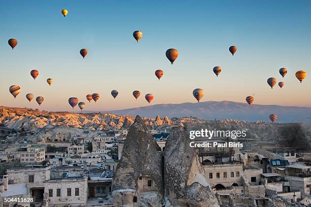 hot air balloons floating over rock formations at sunrise goreme village , cappadocia, anatolia, turkey - göreme stock pictures, royalty-free photos & images