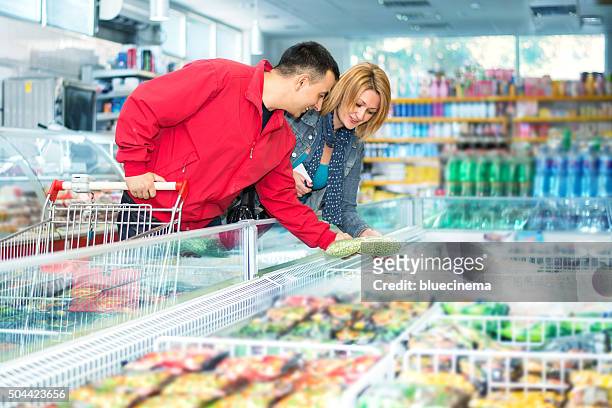 couple in supermarket near frozen food - frozen food stock pictures, royalty-free photos & images