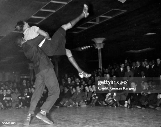 Couple competing in Savoy Ballroom Lindy Hop contest as crowd looks on.