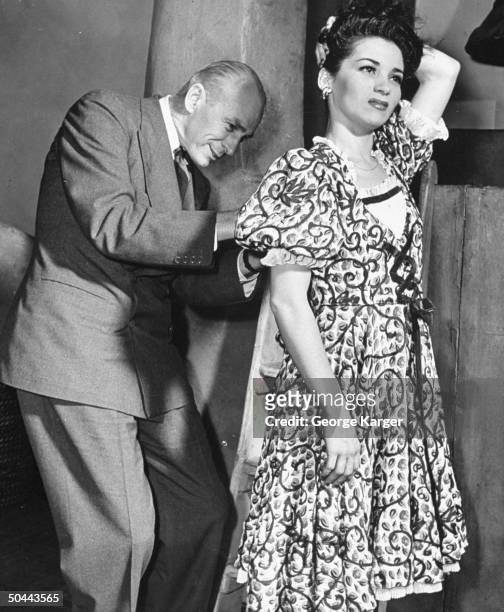 Producer George Abbott helping actress Diosa Costello with her costume backstage of his play Too Many Girls.