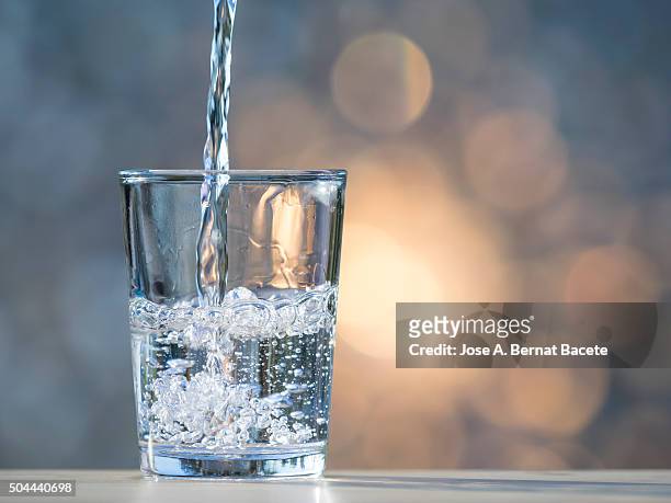water jet filling a glass of crystal. - wasserglas stock-fotos und bilder