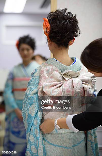 Stylist adjusts the obi sash of young woman's furisode-style kimono for her Coming of Age Day ceremony at a photo studio in Kawasaki City, Kanagawa...