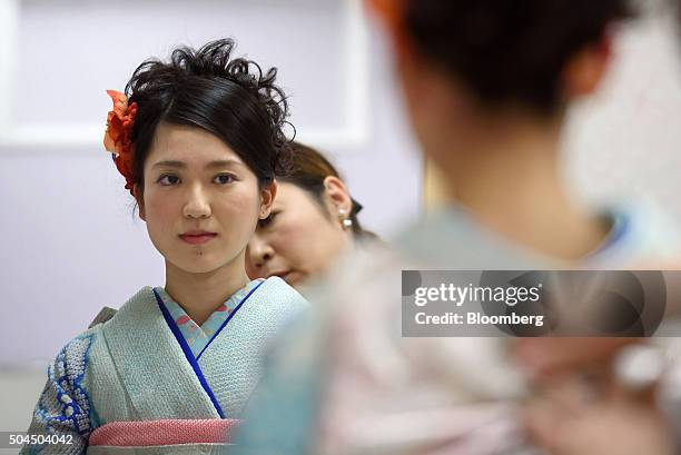 Stylist adjusts the obi sash of young woman's furisode-style kimono for her Coming of Age Day ceremony at a photo studio in Kawasaki City, Kanagawa...