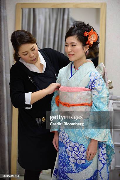 Stylist adjusts the obi sash of young woman's furisode-style kimono for her Coming of Age Day ceremony at a photo studio in Kawasaki City, Kanagawa...