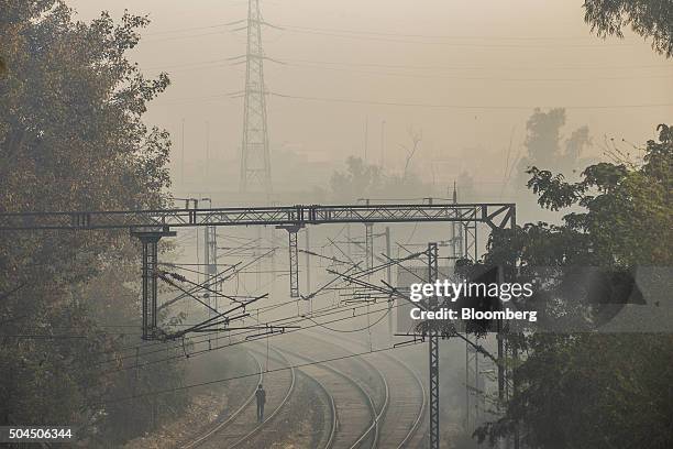 Pedestrian walks along rail tracks shrouded in smog in New Delhi, India, on Monday, Jan. 11, 2016. A 2-judge Delhi High Court panel headed by Chief...