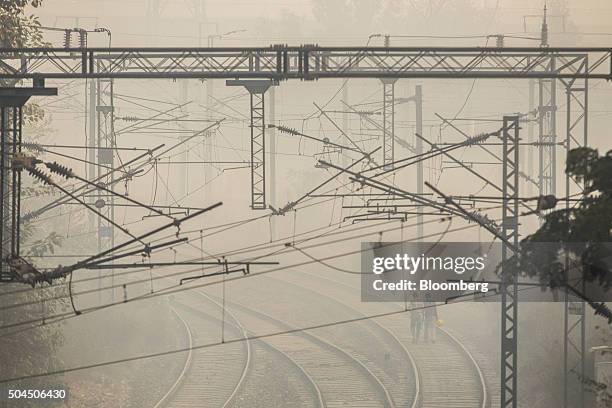 Workers walk along a rail track shrouded in smog in New Delhi, India, on Monday, Jan. 11, 2016. A 2-judge Delhi High Court panel headed by Chief...