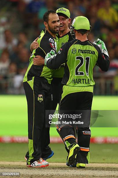 Fawad Ahmed, Michael Hussey and Chris Hartley of the Thunder celebrate after Ahmed took the wicket of Tom Cooper of the Renegades during the Big Bash...