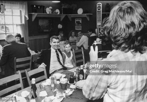 Lt. Col. Oliver North with daughter Sarah having their picture taken by a waitress at restaurant.