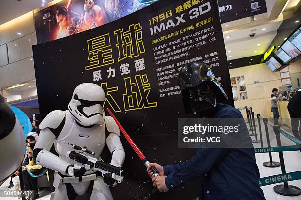 Fan wearing a black mask poses with a solider when waits for the premiere of "Star Wars: The Force Awakens" at a cinema on January 9, 2015 in...