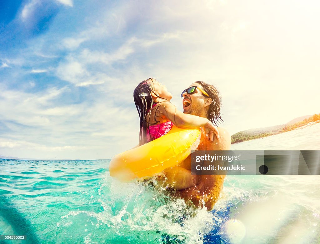 Father and daughter jumping and having fun together in sea