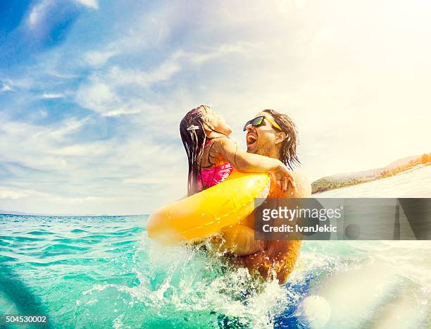 father and daughter jumping and having fun together in sea - beach holiday stock pictures, royalty-free photos & images