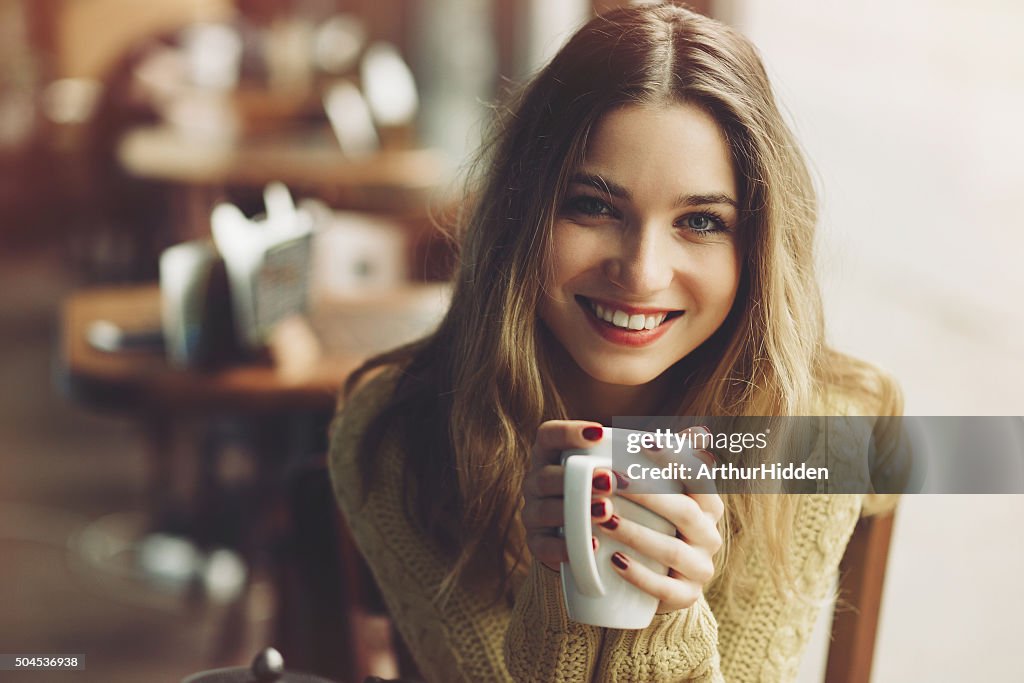 Charming girl drinking cappuccino and eating cheesecake