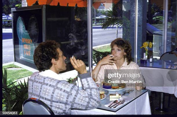 Couple smoking at restaurant after anti-smoking law was rescinded due to dwindling patronage.