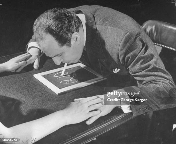 Magician and psychic investigator Joseph Dunninger demonstrating slate writing used in seances.