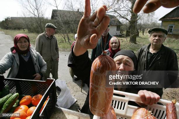 An old woman buys some food as others wait for their turn in a Belarus' village of Tulgovichi inside the 30km exlusion zone, some 370 km outside...