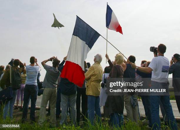 Des personnes regardent le décollage du supersonique Concorde en bout de piste de l'aéroport de Roissy-Charles de Gaulle, le 11 mai 2003 aux abords...