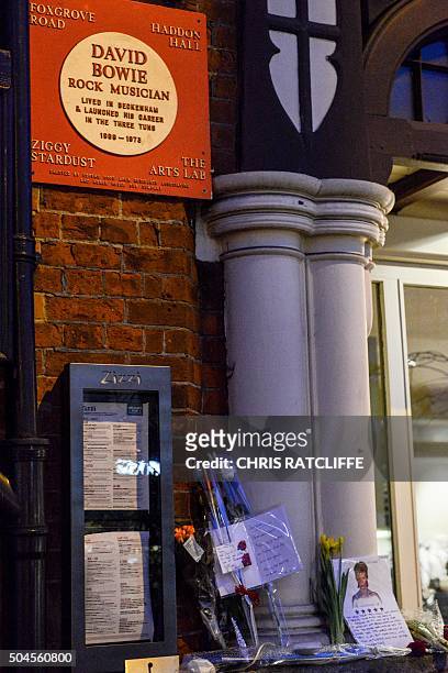 Tributes are seen been a plaque commemorating British musician David Bowie, outside a restaurant in Beckenham, south London, on January 11 following...