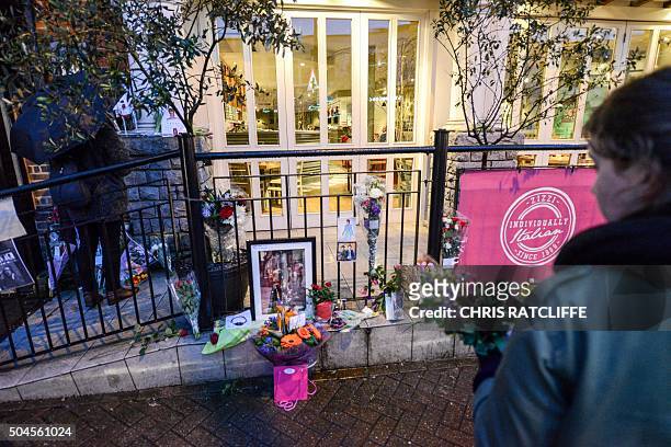 People look at flowers laid in tribute to British musician David Bowie, outside a restaurant in Beckenham, south London, on January 11 following the...