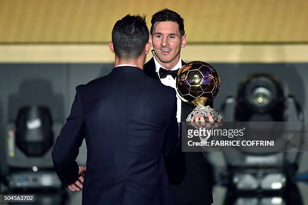 Barcelona and Argentina's forward Lionel Messi holds his trophy as he shakes hands with Real Madrid and Portugal's forward Cristiano Ronaldo after...