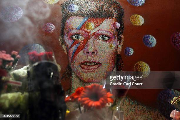 Flowers are laid beneath a mural of David Bowie in Brixton on January 11, 2016 in London, England. British music and fashion icon David Bowie died...
