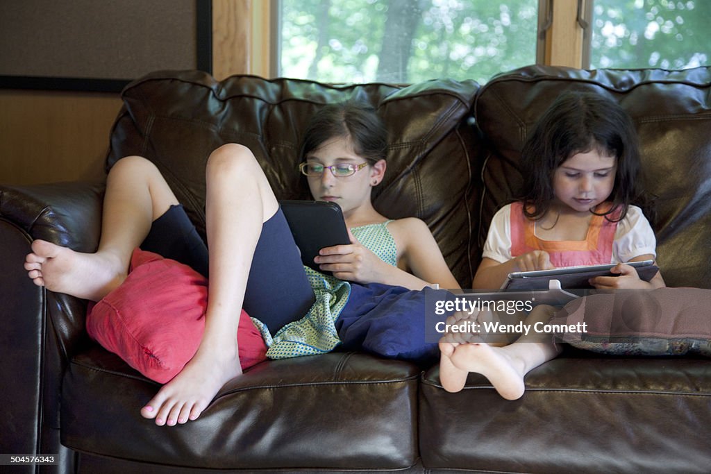 Sisters using electronic tablets