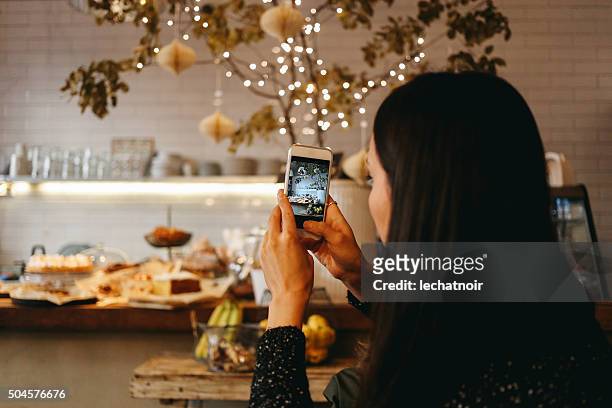 young brunette taking a photo with a smartphone - automatiskt postproduktionsfilter bildbanksfoton och bilder