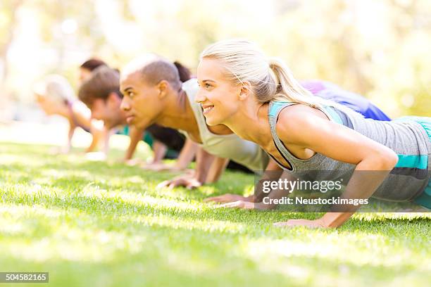 group of people doing push-ups at bootcamp workout class - military camp stock pictures, royalty-free photos & images