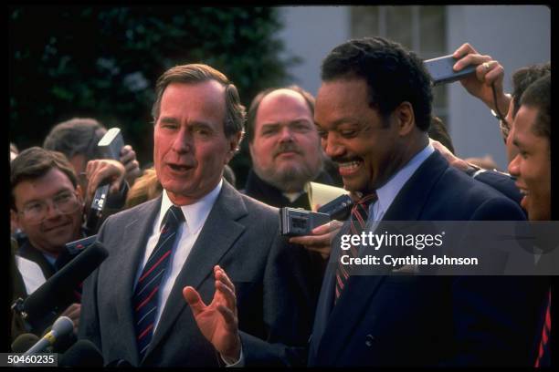 American President George HW Bush speaks as American religious and Civil Rights leader Reverend Jesse Jackson smiles, during a press conference...