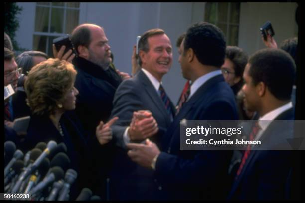 American President George HW Bush shakes hands with American religious and Civil Rights leader Reverend Jesse Jackson during a press conference...