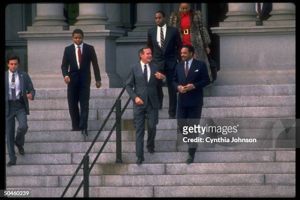 American President George HW Bush and American religious and Civil Rights leader Reverend Jesse Jackson walk down the steps outside the Old Executive...