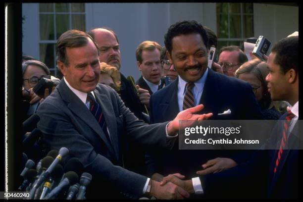 American President George HW Bush shakes hands with Jesse Jackson Jr and the latter's father, American religious and Civil Rights leader Reverend...