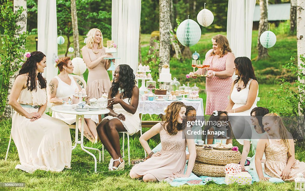 Eleven women having a garden party with dessert table