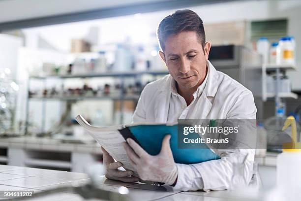 masculino químico leitura dos dados médicos em laboratório. - artigo da imprensa - fotografias e filmes do acervo