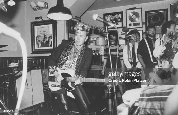 Stray Cats guitarist Brian Setzer performing w. People in background at party thrown for guitarist Les Paul; Hard Rock Cafe.
