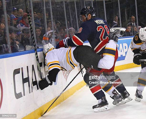 Dominic Moore of the New York Rangers pushes Landon Ferraro of the Boston Bruins into the boards during the third period at Madison Square Garden on...