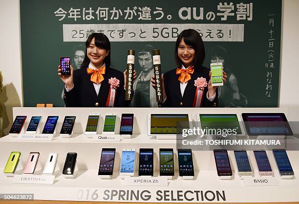 Models pose behind Japanese mobile communication company KDDI's 2016 spring model handsets during its press preview in Tokyo on January 12, 2016....