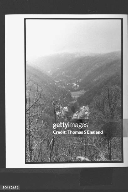 Overall view of mountain-lined valley w. Houses & town buildings nestled at the bottom.