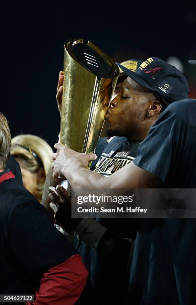 Derrick Henry of the Alabama Crimson Tide celebrates by kissing the College Football Playoff National Championship Trophy after defeating the Clemson...