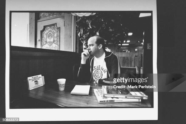 Payne Harrison author of STORMING THE INTREPID sitting at Grandy's restaurant wearing a Texas A and M t-shirt holding a pen; there are a notepad and...