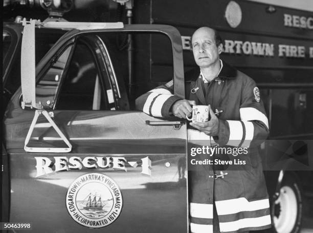 John Farrar in fireman's jacket standing w. A rescue truck at Edgartown fire station; he was the head of search and rescue for the the volunteer fire...